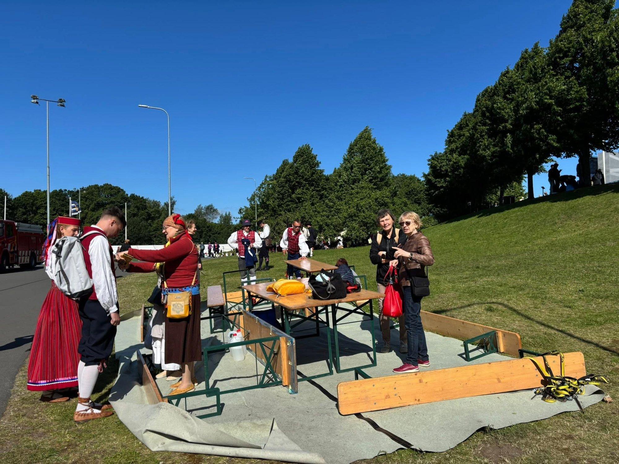 Rahvarõivaabi telk lendas tormituulega minema. Abilised parandavad pastlaid ja seelikuid lageda taeva all